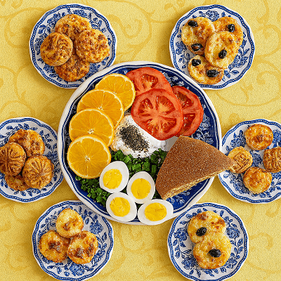 Cultural pastry excellence displayed in a lavish Arabic breakfast spread featuring soup, dates, and savory pastries on blue-decorated plates.