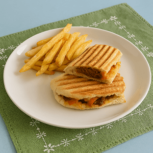 flavor-packed bread fold served with crispy golden fries on a white plate placed over a green embroidered napkin.